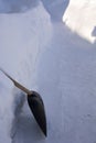 Raking away the snow in the garden. The shovel stands at a high snowdrift. There is a lot of snow in the garden in winter.