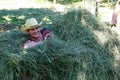 Woman laying in the hay. Putting the grass on the trailor. Farm chores, working on a field.