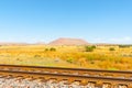 Raliway tracks across flat plains of New Mexico with distant mesa landforms under blue sky Royalty Free Stock Photo