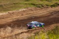 Rally off-road car make a turn with the clouds and splashes of sand, gravel and dust during rally championship