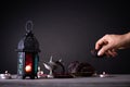 Ramadan food and drinks concept. Woman hand reaches out to a plate with date with Ramadan Lantern with arabian lamp, wood rosary,