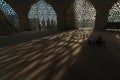 Muslim man praying in the mosque. Shadows of windows on the ground