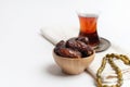 Ramadan Kareem Festival, Dates on wooden bowl with cup of black tea and rosary on white isolated background