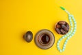 Ramadan Kareem Festival, Dates on wooden bowl with cup of black tea and rosary on yellow background Royalty Free Stock Photo