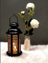 The Ramadan lantern is black, luminous , and its sides are decorated with wooden decorations, placed next to a small vase