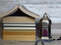 Ramadan Ramazan time celebration. A pile of home shaped old books, silver Ramadan lantern, black chaplet, worry-beads.