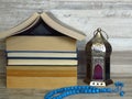 Ramadan Ramazan time celebration. A pile of home shaped old books, silver Ramadan lantern, blue turquoise chaplet, worry-beads.