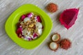 Rambutan, dragon fruits, multigrain, and granola with yogurt in green bowl for diet meal