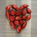 Rambutan and dragon fruits organised in heart shape on brown bamboo mat background