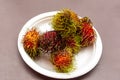 Rambutan red and ripe tropical fruit on a white plate close-up Royalty Free Stock Photo