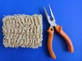 Ramen noodles next to the pliers - concept to fix anything using noodles -  blue background Royalty Free Stock Photo