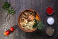 Top view ramen with seafood, spices and greens on a wooden background.