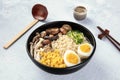 Ramen. Soba noodles with boiled eggs, mushrooms, and vegetables, with sake, wooden spoon, and chopsticks Royalty Free Stock Photo