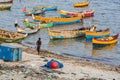 Unidentified poor local Traditional fisherman are fishing on the beach with very small colored wood boats.