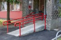 Ramp for wheelchair entry with metal handrails. Disabled persons care in urban environment