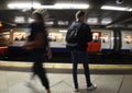 Random passenger people at the underground tube station with moving train motion blurred. London England