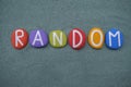 Random, creative word composed with multi colored stone letters over green sand