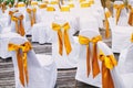 A group of white spandex chairs cover with gold organza sash for beach wedding venue arrangement