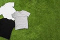 Randomly scattered mens different coloured T-shirts on grass background