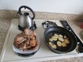 Range with cooked potato, pot and plate with meat.