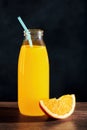 Range juice in a glass bottle with straw and an orange slice on wooden table Royalty Free Stock Photo