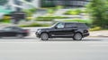 Range Rover L405 side view. Premium SUV black color driving against a background of urban buildings. Full size luxury crossover in