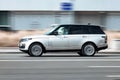 Range Rover L405 side view. Premium SUV silver color driving against a background of urban buildings. Full size luxury crossover Royalty Free Stock Photo