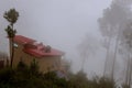 Mountain cottage covered by fog and low clouds. Scenic, environment. Royalty Free Stock Photo