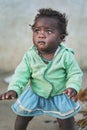 Ranohira, Madagascar - April 29, 2019: Malagasy girl toddler, in torn clothes, sweater inside out, barely standing on ground,