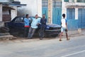 Ranohira, Madagascar - April 29, 2019: Three unknown local men leaning on old broken car in evening, resting and chatting. Another