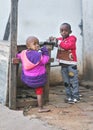 Ranohira, Madagascar - April 29, 2019: Two unknown Malagasy kids standing by empty wooden market stall on the street, looking into