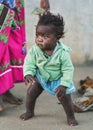 Ranohira, Madagascar - April 29, 2019: Unknown little Malagasy kid, barefoot, barely standing, mother stands near. People in