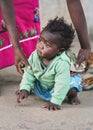 Ranohira, Madagascar - April 29, 2019: Unknown little Malagasy kid, barefoot, crawling on dusty footpath, mother helping her