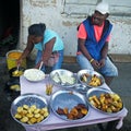 Ranohira, Madagascar - April 29, 2019: Unknown Malagasy woman cooks on the street, deep frying various coated vegetables, another