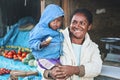 Ranohira, Madagascar - April 29, 2019: Unknown Malagasy woman holding her baby son on hands, smiling, blurred market stall