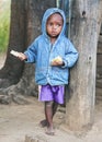 Ranohira, Madagascar - April 29, 2019: Unknown young Malagasy kid in blue denim jacket and shorts, standing at wooden pillar,