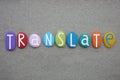 ranslate, creative word composed with multi colored stone letters over beach sand Royalty Free Stock Photo