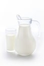 ransparent jug and a glass completely filled with fresh cow milk stand on a clean white background. Royalty Free Stock Photo