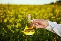 Rapeseed oil bottle in hand of an agronomist or biologist on background rape field Royalty Free Stock Photo