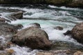 Rapid current Water flow at small shallow mountain river at summer day. Stones stick out of the clear water. Close up