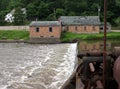 Rapid flow of river dam with a brick house building on the grass area Royalty Free Stock Photo