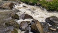 The rapid flow of waterfall water hits a large rock