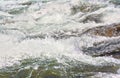 Rapid spring river flowing over rocks on sunny day, forming white water waves, closeup detail - abstract nature Royalty Free Stock Photo