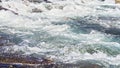 Rapid spring river flowing over rocks on sunny day, forming white water waves, closeup detail - abstract nature background Royalty Free Stock Photo