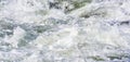 Rapid spring river flowing over rocks on sunny day, forming white water waves, closeup detail - abstract nature background Royalty Free Stock Photo