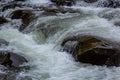 Rapids of mountain rivers with fast water and large rocky boulders. Rapid flow of a mountain river in spring, close-up Royalty Free Stock Photo