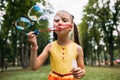 Rapt little girl blows bubbles in the park.