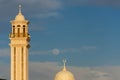 A rare daytime full moon with a blue sky behind the minarets of a local mosque in the United Arab Emirates