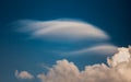 Rare Lenticular cloud Altocumulus lenticularis on top of a cumulus cloud in front of a blue sky Royalty Free Stock Photo