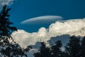 Rare Lenticular cloud Altocumulus lenticularis on top of a cumulus cloud in front of a blue sky Royalty Free Stock Photo